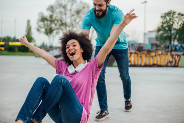 istock Ecstatic woman shouting in joy while her boyfriend is pushing her on the skateboard 975790442