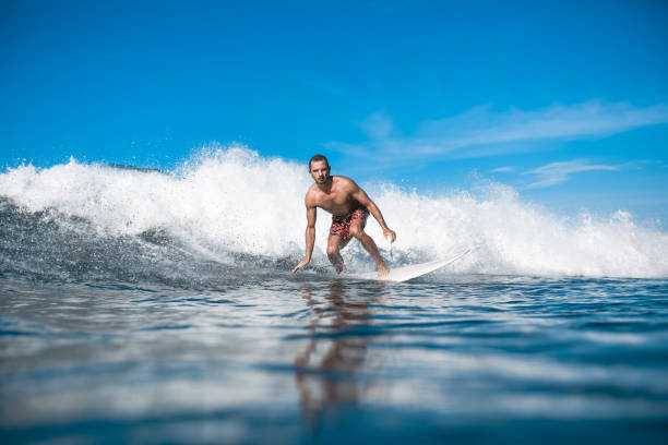 istock handsome sporty man riding on waves on sunny day 975799140