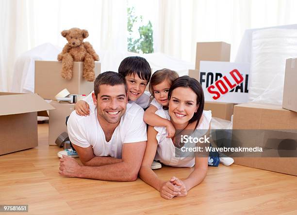 Happy Family Relaxing While Moving House Stock Photo - Download Image Now - Family, Moving House, Box - Container