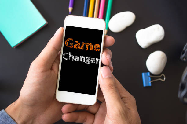 istock Game changer, text message on screen at hands take smartphone, black table with office supplies backdrop background . business concept. 975847470