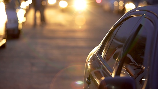 Automobile slowly driving on parking lot during magic sunset, auto park