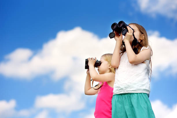 istock Two cute little girls looking through binoculars on sunny summer day 975866918