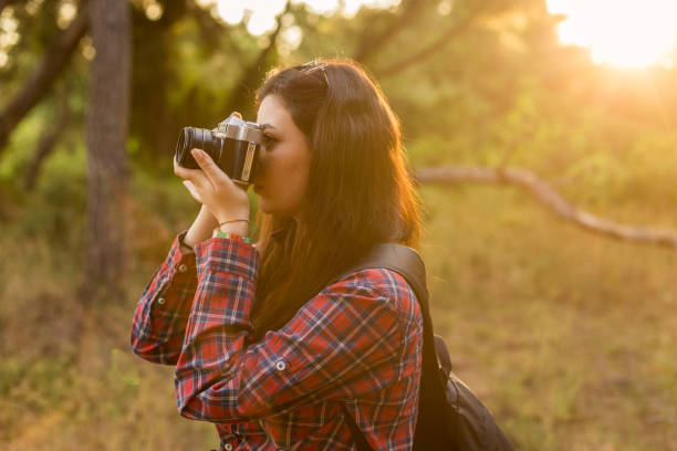 istock Young woman photographing in forest 975876192