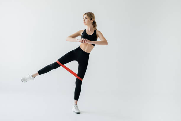 istock young athletic woman exercising with rubber tape isolated on grey 975888110