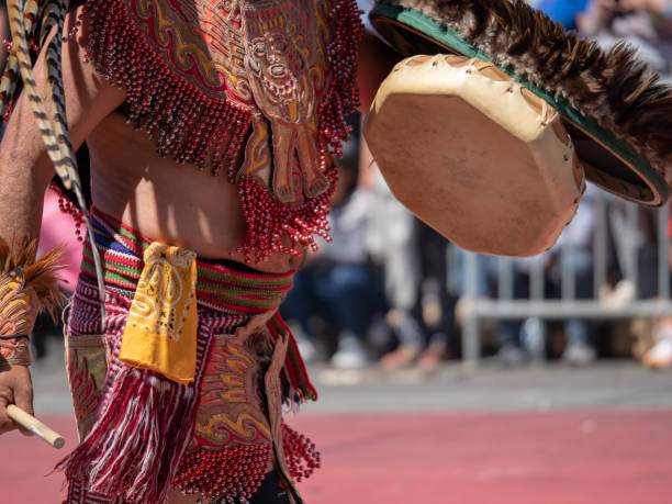 istock Man dressed in traditional Aztec garb beats on a drum during a march 975898300