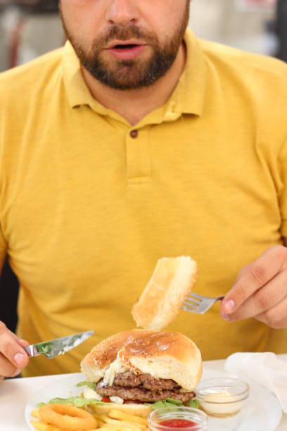 istock Young man eating an Hamburger 975912450