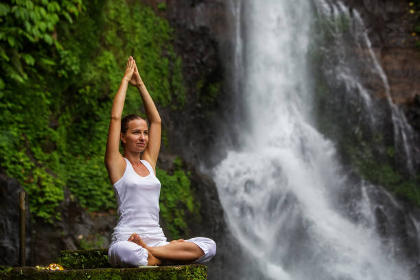 istock Woman practices yoga at Gitgit waterfall on Bali in indonesia 975922106