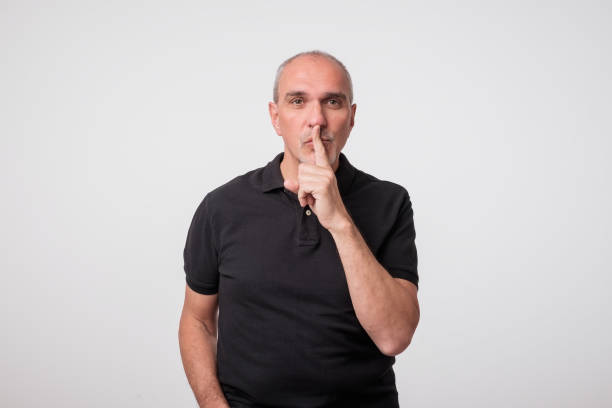 istock handsome old man in black t-shirt with finger on his lips. 975953322