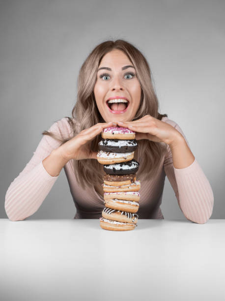 istock Young beautiful woman with many donuts is smiling with open mouth 975969582