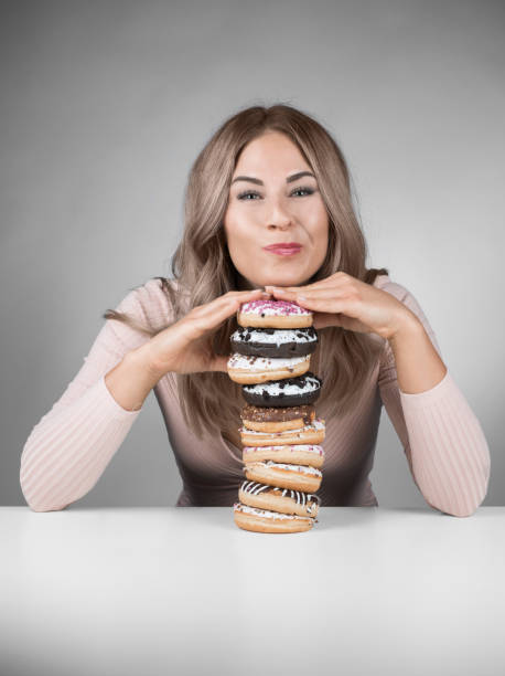 istock Young beautiful woman with many donuts 975969584