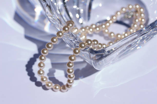Abstract background macro of a beautiful modern lead crystal glass heart bowl and pearls This abstract background features a close-up view of a beautiful modern heart-shaped lead crystal glass bowl accented with a vintage string of pearls. lead cut glass crystal stemware stock pictures, royalty-free photos & images