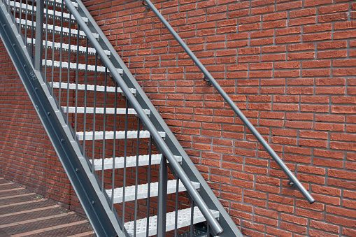Wide fire escape staircase with railing on red brick wall