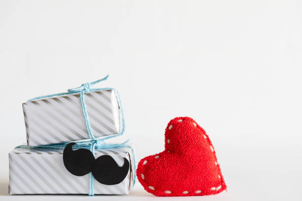 istock Happy fathers day concept. Stack of beautiful gift box with mustache and handmane red heart on white background. 976012070
