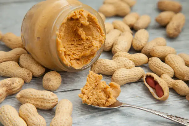 Photo of an open jar of peanut butter with spoon