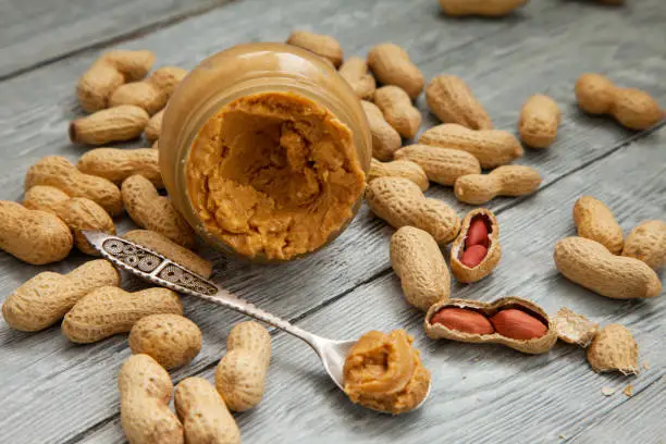 Photo of an open jar of peanut butter with spoon
