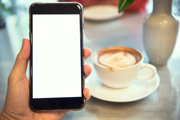 istock hand holding mobile phone with blank white screen in cafe. mockup advertising. 976033748