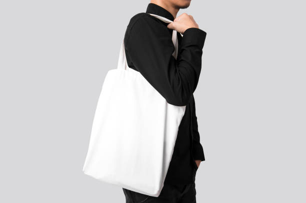 Man is holding bag canvas fabric for mockup blank template isolated on gray background. stock photo