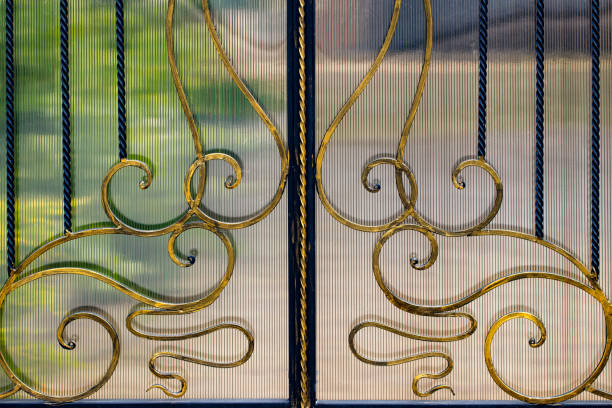 A closed forged metal gate looking onto a garden path.