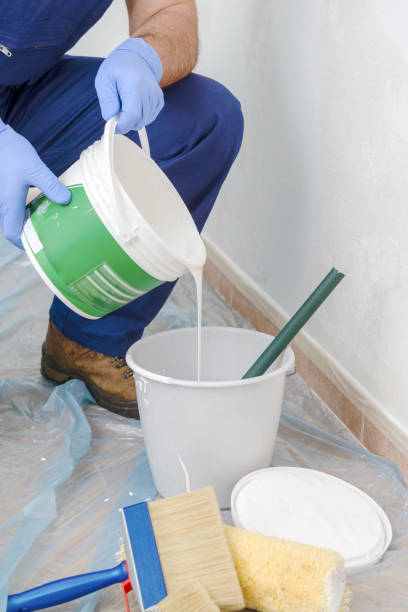 istock Painter paints the wall with the tint of white. 976052984
