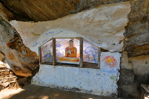 Woman praying in front of Cross-legged monk by the reclining Buddha at Cave temple (Wat Tham Suwan Khuha), in Phang-Nga province, Thailand