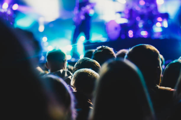 istock A crowded concert hall with scene stage lights, rock show performance, with people silhouette 976090318