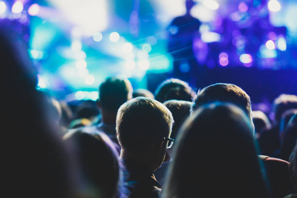 istock A crowded concert hall with scene stage lights, rock show performance, with people silhouette 976090366