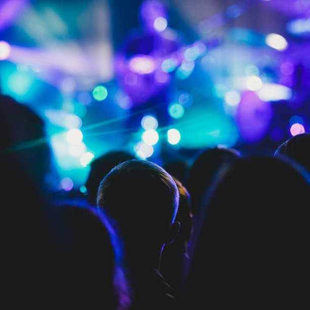 istock A crowded concert hall with scene stage lights, rock show performance, with people silhouette 976094896