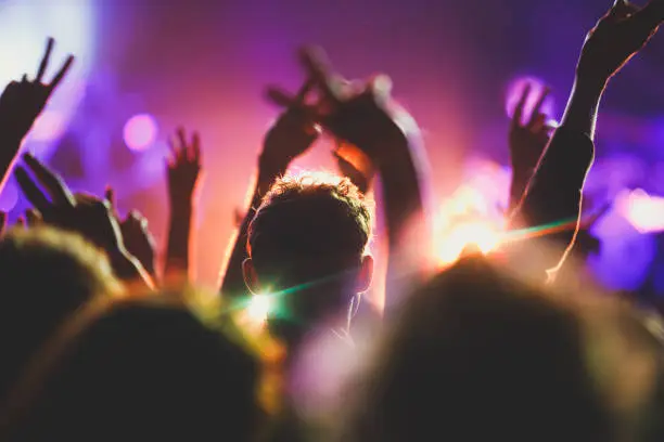 Photo of A crowded concert hall with scene stage lights, rock show performance, with people silhouette