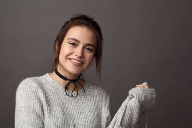 primer plano retrato de una joven atractivo de 18 años en un suéter gris en un estudio sobre un fondo gris - one person one young woman only 18 19 years teenage girls fotografías e imágenes de stock