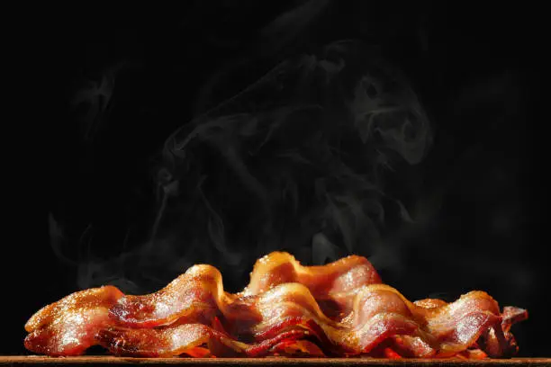 Photo of Pile of Sizzling Bacon Isolated on Black