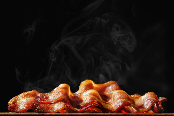 куча шипящих бекона изолированы на черном - bacon стоковые фото и изображения