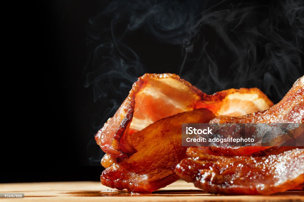 Bacon caliente con vapor aislado en negro - Foto de stock de Tocino ahumado libre de derechos