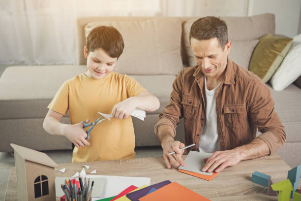 Cheerful parent and child folding figures from papers