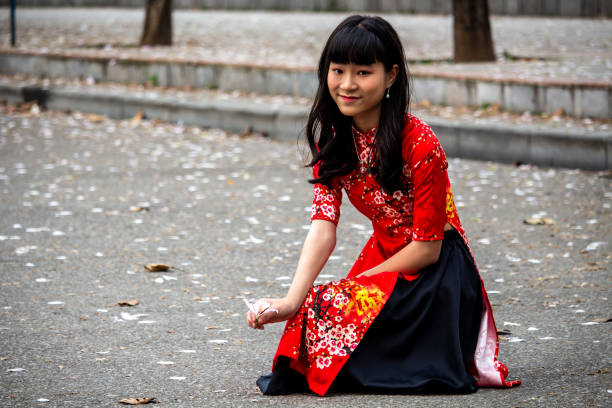 Hanoi, Vietnam - March 16, 2018: Local girl posing on the street with a lotus flower in her hands