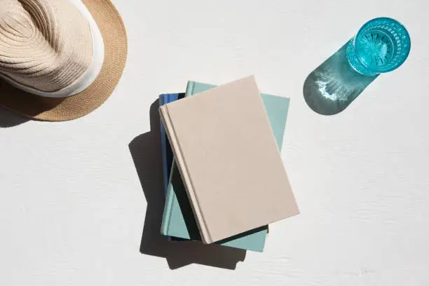 Photo of Flat lay of sun hat books and water