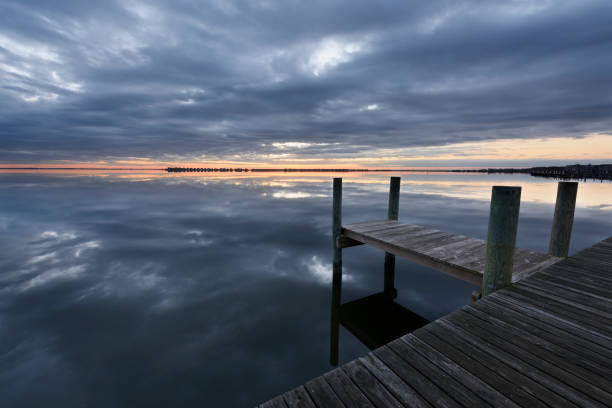 istock Dock on Ocean Inlet with Dramatic Clouds Reflecting in Water 976237286