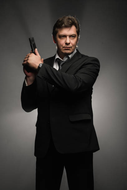 istock Handsome middle aged detective man with gun on dark background 976263316