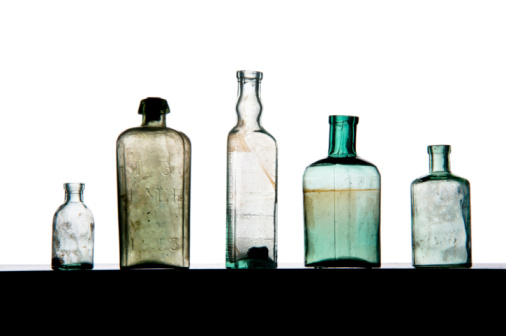 A collection of antique bottles of various sizes, shapes and colors displayed at a Cape Cod flea market.