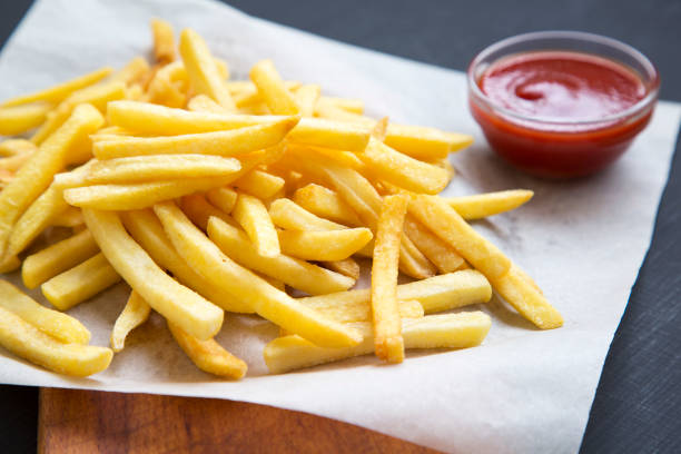 istock French fries with ketchup over black background, side view. Closeup. 976294436