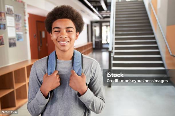 Portrait Of Male High School Student Standing By Stairs In College Building Stock Photo - Download Image Now