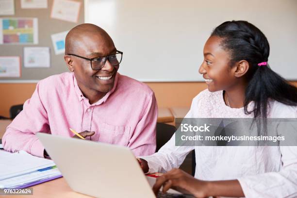 High School Tutor Giving Female Student One To One Tuition At Desk Stock Photo - Download Image Now
