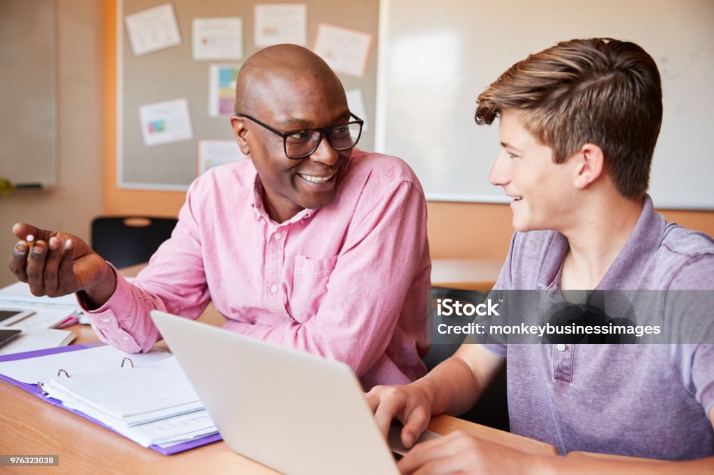 Tutor de colegial dando aulas de um para um estudante do sexo masculino na mesa - Foto de stock de Professor Particular royalty-free