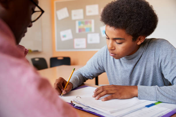 istock High School Tutor Giving Male Student One To One Tuition At Desk 976323040