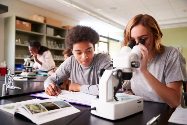 High School Students Looking Through Microscope In Biology Class High School Students Looking Through Microscope In Biology Class science class stock pictures, royalty-free photos & images