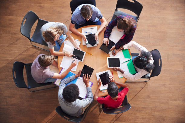 istock Overhead Shot Of High School Pupils Using Digital Tablets In Group Study Around Tables 976330922