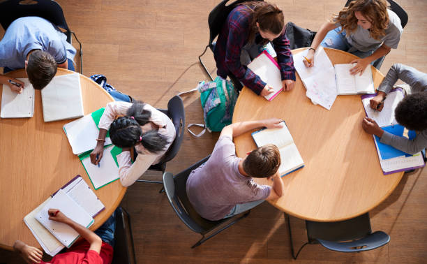 istock Overhead Shot Of High School Pupils In Group Study Around Tables 976330924