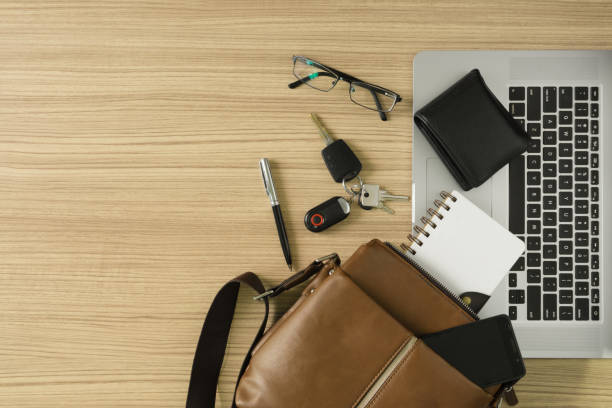 Men's leather bag and laptop on wood background. Men's leather bag with personal items and laptop on wood desk. phone wallet keys stock pictures, royalty-free photos & images