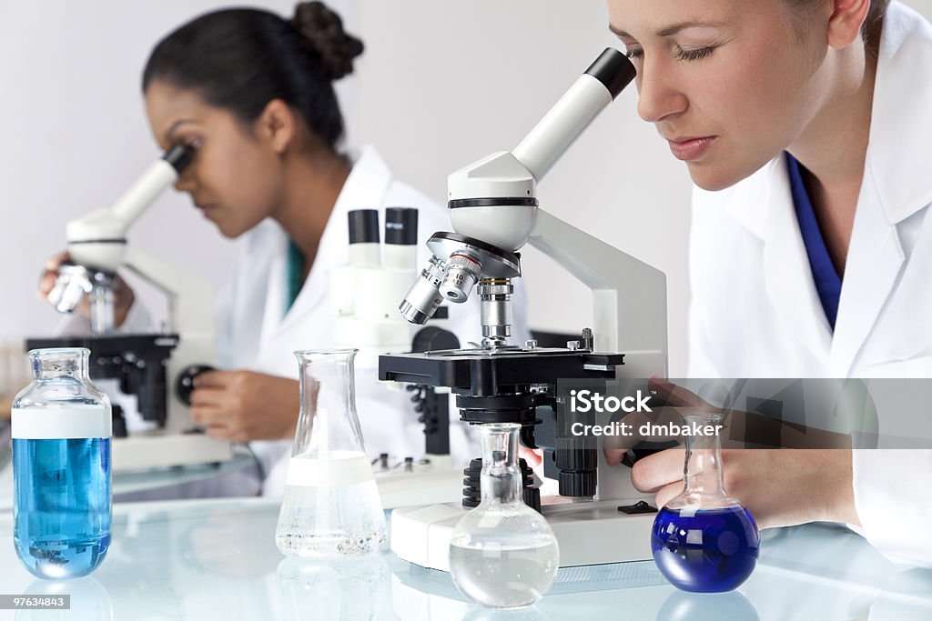 Equipe de investigação científica feminino usando microscópios em laboratório - Foto de stock de Adulto royalty-free