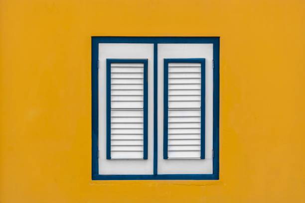istock Yellow wall with a white window. Retro photo. 976358824