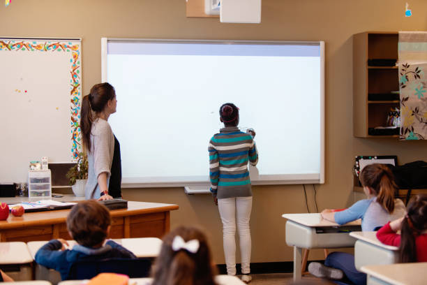 istock African ethnic Shcoolgirl writing lesson in interactive whiteboard in classroom 976359292